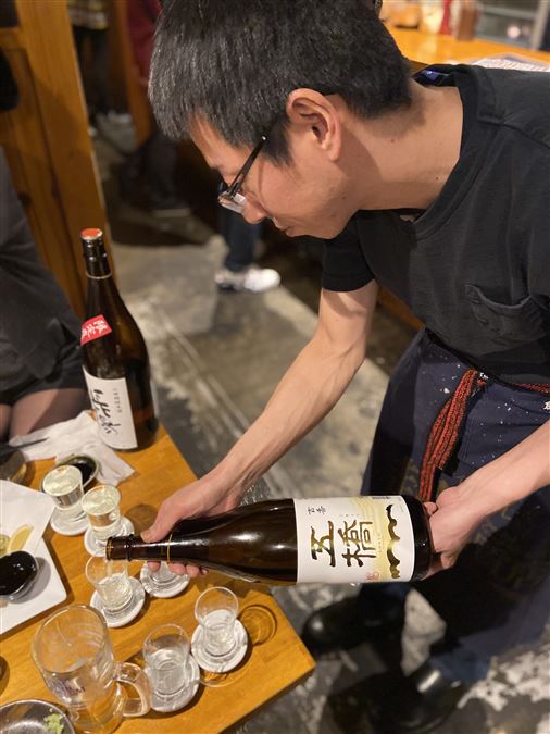 Proprietario di un bar ad Hiroshima che versa sake (non nelle "classiche ciotoline" che usiamo in Italia).